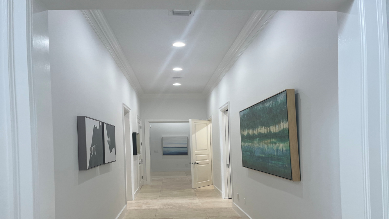 White hallway with recessed lighting and artwork